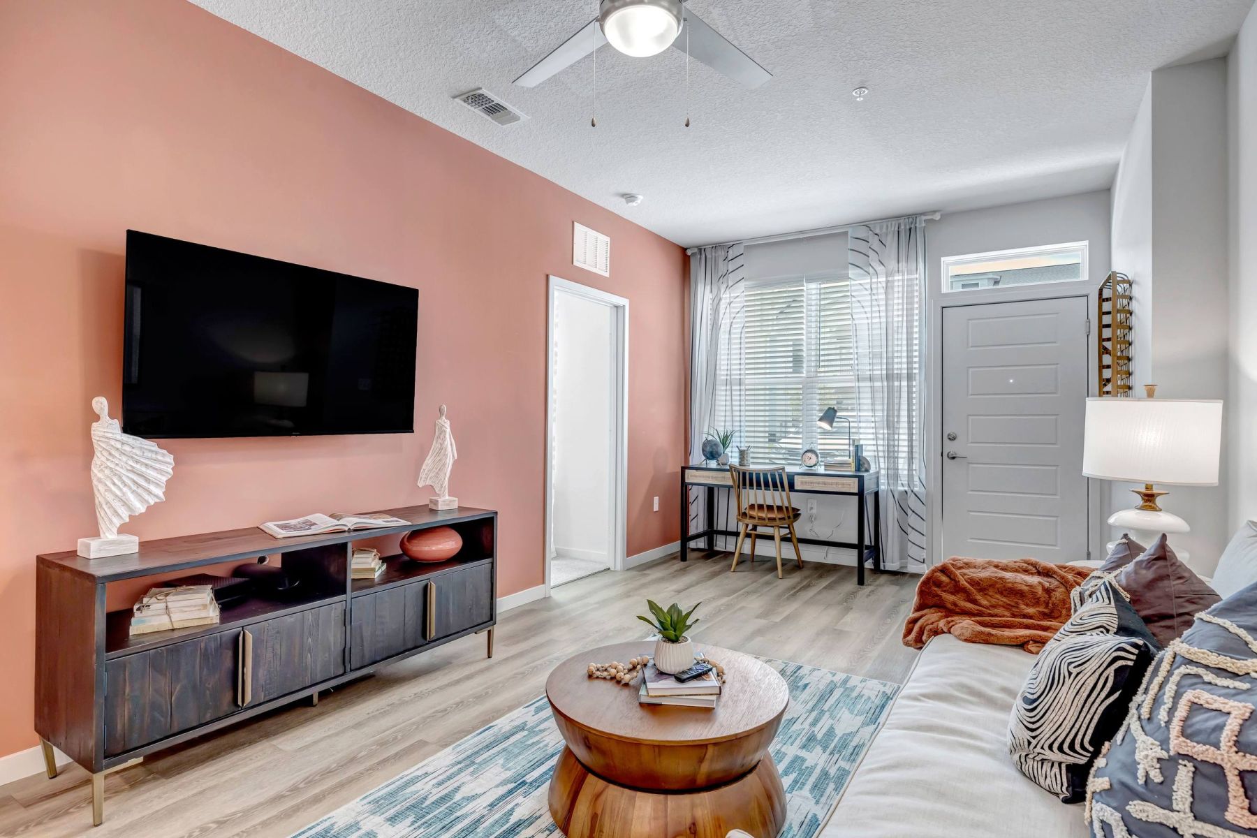 Empty room with wood floors, ceiling fan, and sliding glass door leading to a patio with vertical blinds at Apex West Midown.
